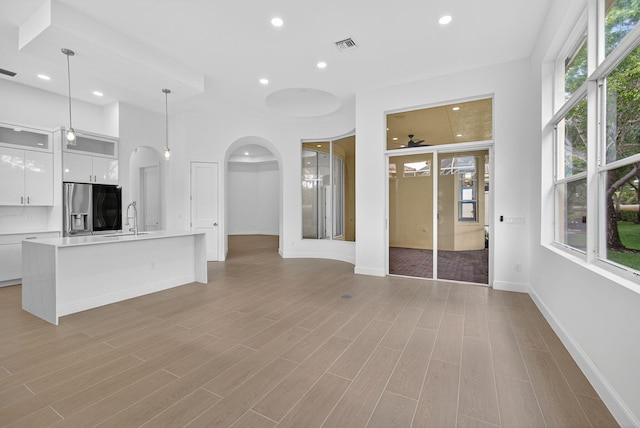 8873 Via Brilliante, Wellington, FL 33411 - unfurnished living room featuring arched walkways, recessed lighting, light wood-style flooring, and a ceiling fan