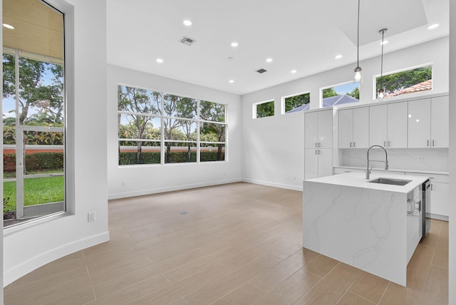 8873 Via Brilliante, Wellington, FL 33411 - kitchen featuring recessed lighting, decorative light fixtures, white cabinets, light stone countertops, and a center island with sink