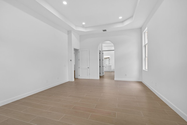 8873 Via Brilliante, Wellington, FL 33411 - spare room with arched walkways, a raised ceiling, recessed lighting, and light wood-style floors