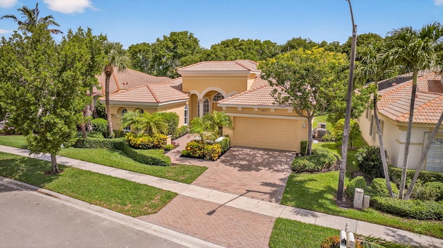 8873 Via Brilliante, Wellington, FL 33411 - mediterranean / spanish-style home with stucco siding, a garage, a tiled roof, decorative driveway, and a front lawn