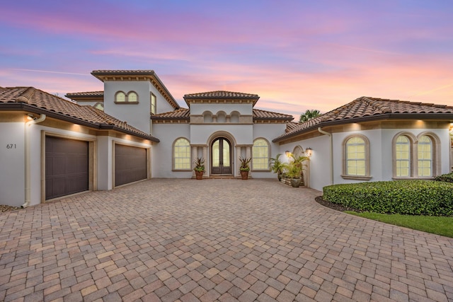 671 Indian River Dr, Melbourne, FL 32935 - mediterranean / spanish-style house with an attached garage, decorative driveway, stucco siding, french doors, and a tiled roof