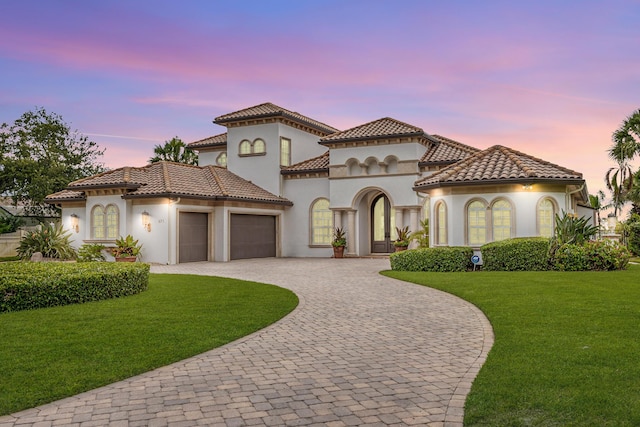 671 Indian River Dr, Melbourne, FL 32935 - mediterranean / spanish home with an attached garage, curved driveway, stucco siding, a lawn, and a tiled roof