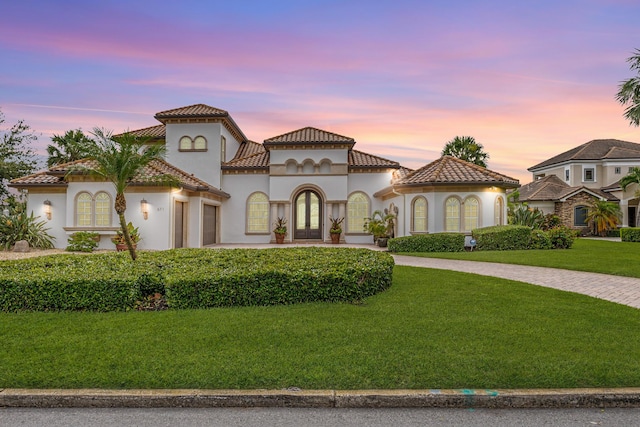 671 Indian River Dr, Melbourne, FL 32935 - mediterranean / spanish-style home featuring curved driveway, a garage, a front yard, stucco siding, and a tile roof