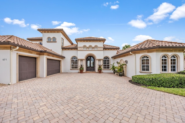 671 Indian River Dr, Melbourne, FL 32935 - mediterranean / spanish-style house featuring french doors, a garage, decorative driveway, stucco siding, and a tiled roof