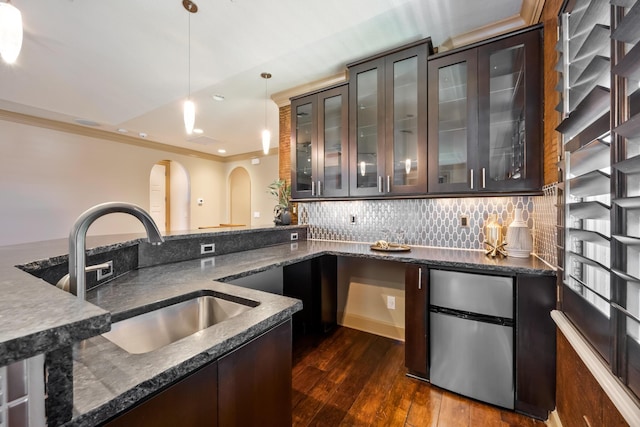 671 Indian River Dr, Melbourne, FL 32935 - bar area featuring arched walkways, freestanding refrigerator, dark wood finished floors, pendant lighting, and tasteful backsplash