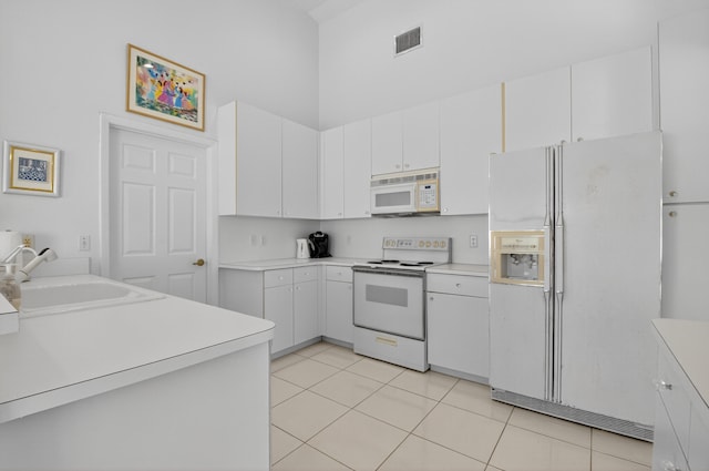 17213 Balboa Point Way, Boca Raton, FL 33487 - kitchen featuring white appliances, light countertops, white cabinets, light tile patterned floors, and a towering ceiling