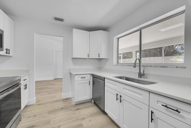 2432 SE Floresta Dr, Port Saint Lucie, FL 34984 - kitchen with appliances with stainless steel finishes, light wood-style floors, white cabinets, and light countertops