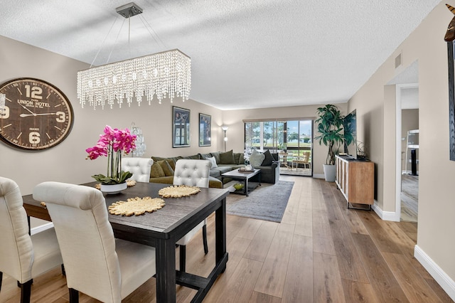 7270 Ashford Pl Unit 104, Delray Beach, FL 33446 - dining space featuring a textured ceiling, a chandelier, and wood finished floors
