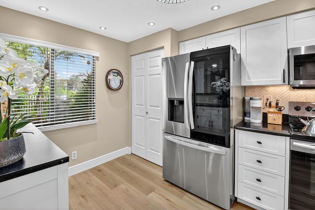 7270 Ashford Pl Unit 104, Delray Beach, FL 33446 - kitchen featuring stainless steel appliances, white cabinets, tasteful backsplash, dark countertops, and light wood-type flooring