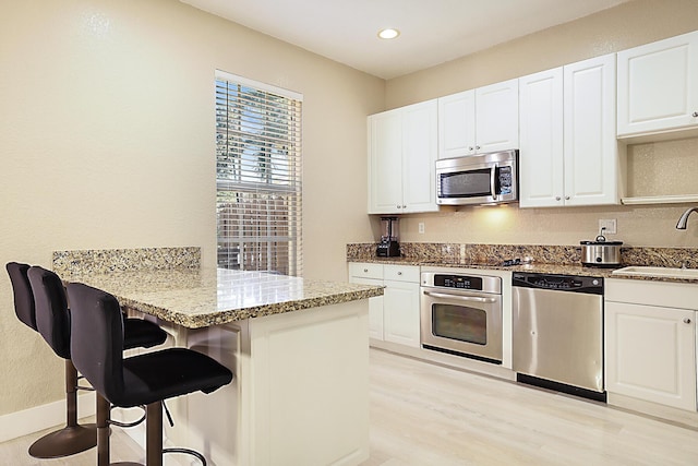 6964 Julia Gardens Dr, Coconut Creek, FL 33073 - kitchen featuring stainless steel appliances, light stone countertops, a peninsula, white cabinets, and recessed lighting