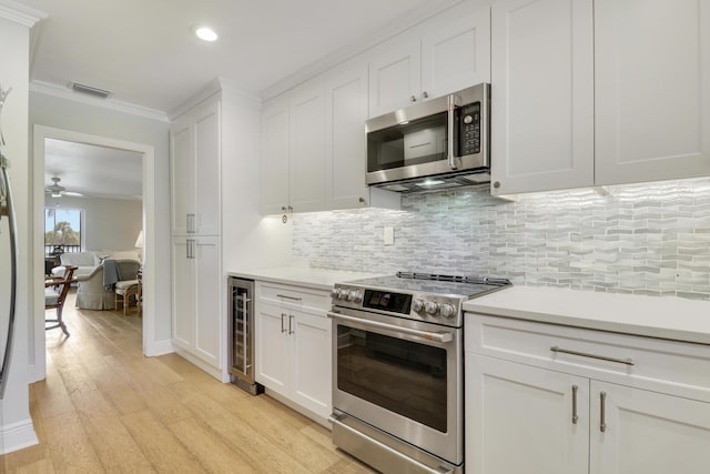 300 Intracoastal Pl Unit 204, Jupiter, FL 33469 - kitchen featuring appliances with stainless steel finishes, beverage cooler, ornamental molding, light countertops, and light wood-style flooring