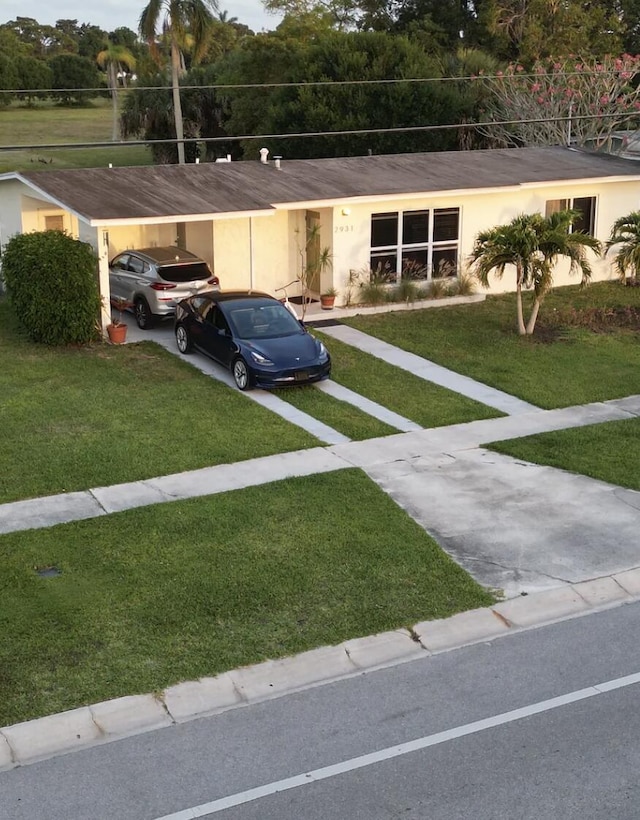 2931 SE Morningside Blvd, Port Saint Lucie, FL 34952 - view of front of property with stucco siding, a front lawn, a carport, and driveway