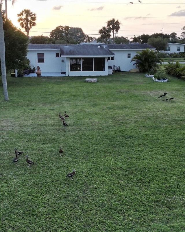 2931 SE Morningside Blvd, Port Saint Lucie, FL 34952 - rear view of house with a lawn, stucco siding, and a sunroom