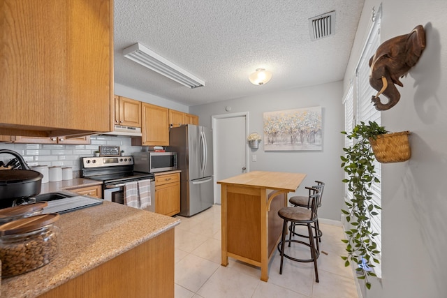 3809 Island Club Cir E, Lake Worth, FL 33462 - kitchen featuring stainless steel appliances, a breakfast bar, tasteful backsplash, under cabinet range hood, and a center island