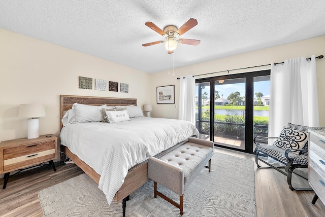 3733 Cape Pointe Cir, Jupiter, FL 33477 - bedroom featuring access to exterior, light wood-type flooring, a water view, a textured ceiling, and ceiling fan