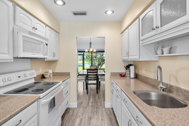 3733 Cape Pointe Cir, Jupiter, FL 33477 - kitchen featuring white appliances, white cabinets, a chandelier, light wood finished floors, and glass insert cabinets