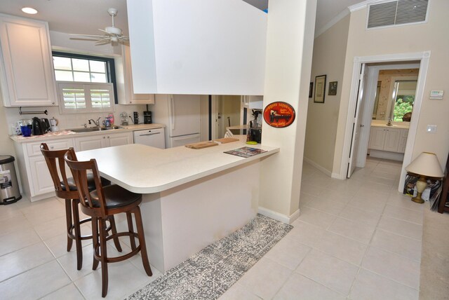 715 SW Balmoral Trce, Stuart, FL 34997 - kitchen with white appliances, light countertops, healthy amount of natural light, a breakfast bar area, and ornamental molding