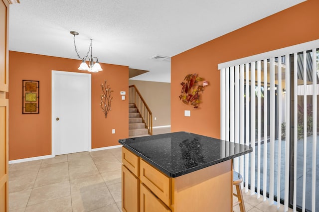 5693 SE Windsong Ln Unit 545, Stuart, FL 34997 - kitchen with hanging light fixtures, light brown cabinets, a center island, a kitchen bar, and dark stone counters
