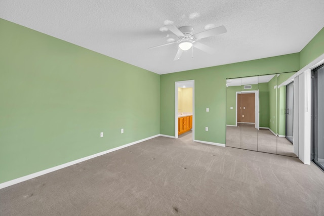 5693 SE Windsong Ln Unit 545, Stuart, FL 34997 - unfurnished bedroom with carpet flooring, a textured ceiling, ceiling fan, and ensuite bath