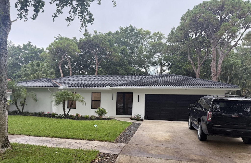 2425 NW 36th St, Boca Raton, FL 33431 - ranch-style house featuring an attached garage, stucco siding, concrete driveway, a tile roof, and a front yard