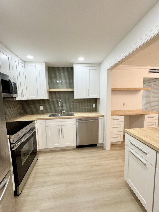 330 Saxony G 330, Delray Beach, FL 33446 - kitchen featuring appliances with stainless steel finishes, open shelves, wooden counters, white cabinets, and decorative backsplash