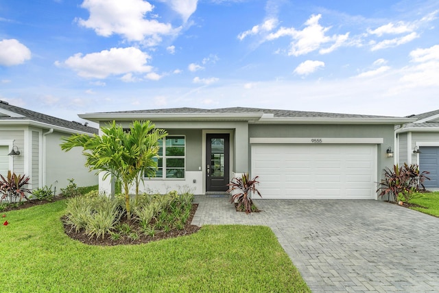 9555 SW Indra Way, Port Saint Lucie, FL 34987 - view of front of home featuring stucco siding, decorative driveway, an attached garage, and a front lawn