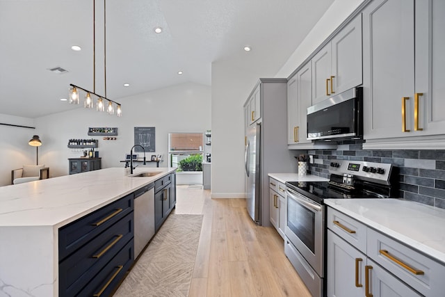 6572 Brookhurst Cir, Lake Worth, FL 33463 - kitchen featuring appliances with stainless steel finishes, vaulted ceiling, recessed lighting, light wood-type flooring, and a center island with sink