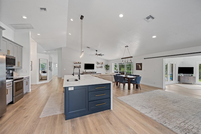 6572 Brookhurst Cir, Lake Worth, FL 33463 - kitchen featuring open floor plan, appliances with stainless steel finishes, lofted ceiling, light wood-type flooring, and a kitchen island with sink