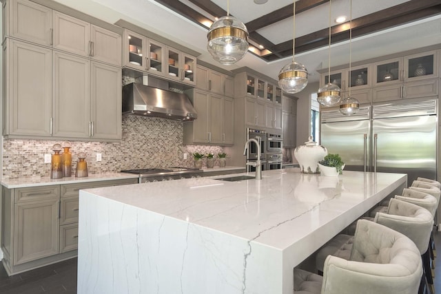 13405 Artisan Cir, Palm Beach Gardens, FL 33418 - kitchen featuring range hood, decorative backsplash, a large island, decorative light fixtures, and light stone countertops