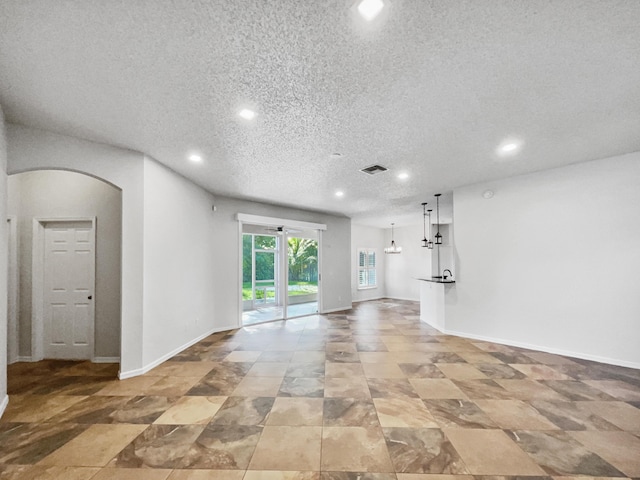 2081 SW Burlington St, Port Saint Lucie, FL 34984 - unfurnished living room featuring arched walkways, recessed lighting, and a textured ceiling