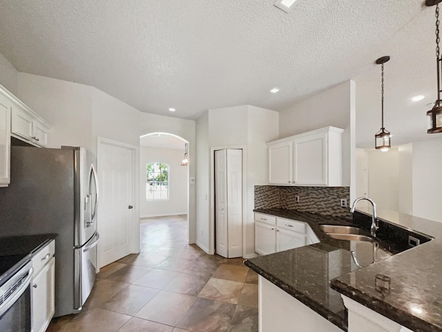2081 SW Burlington St, Port Saint Lucie, FL 34984 - kitchen featuring arched walkways, white cabinetry, dark stone counters, light tile patterned flooring, and a textured ceiling
