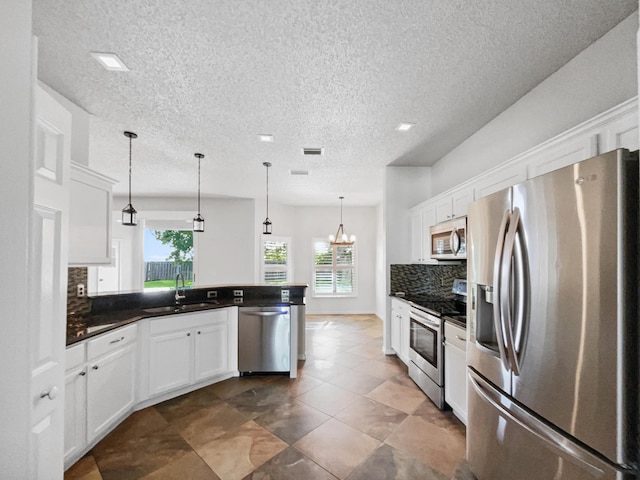 2081 SW Burlington St, Port Saint Lucie, FL 34984 - kitchen featuring stainless steel appliances, tasteful backsplash, a peninsula, dark countertops, and white cabinets
