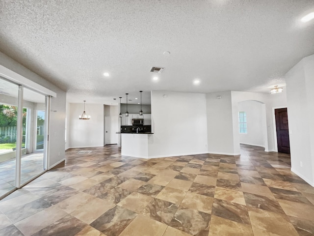 2081 SW Burlington St, Port Saint Lucie, FL 34984 - unfurnished living room featuring a textured ceiling, recessed lighting, a chandelier, and arched walkways