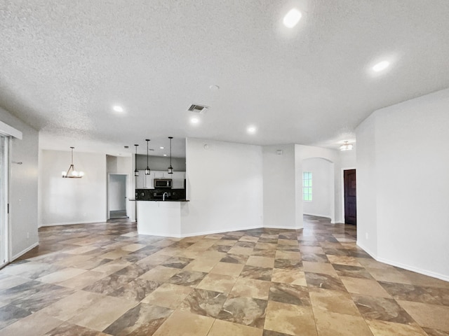2081 SW Burlington St, Port Saint Lucie, FL 34984 - unfurnished living room featuring recessed lighting, arched walkways, a chandelier, and a textured ceiling