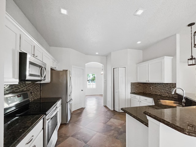 2081 SW Burlington St, Port Saint Lucie, FL 34984 - kitchen with appliances with stainless steel finishes, arched walkways, white cabinetry, decorative backsplash, and a textured ceiling