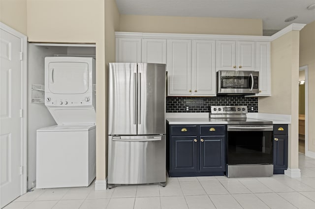 407 SW Fairway Lndg, Port Saint Lucie, FL 34986 - kitchen with stainless steel appliances, stacked washer and clothes dryer, light countertops, backsplash, and white cabinetry