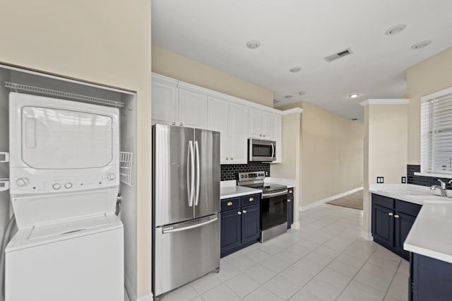 407 SW Fairway Lndg, Port Saint Lucie, FL 34986 - kitchen featuring appliances with stainless steel finishes, stacked washing machine and dryer, blue cabinetry, decorative backsplash, and recessed lighting