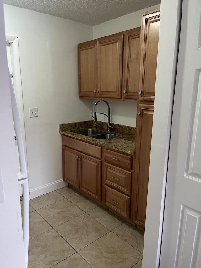 4316 Forest Rd, West Palm Beach, FL 33406 - kitchen with brown cabinets, a textured ceiling, dark stone counters, and light tile patterned floors