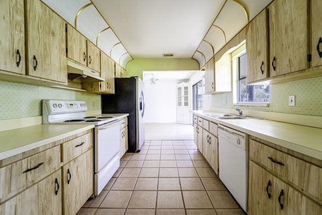 kitchen featuring white appliances, under cabinet range hood, light countertops, light brown cabinets, and wallpapered walls