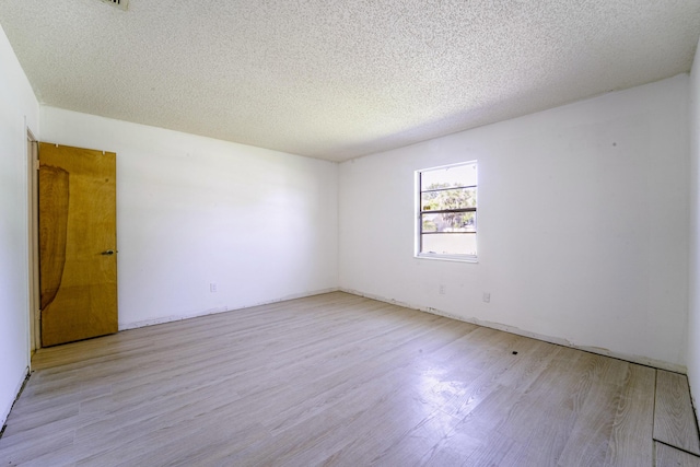 spare room featuring light wood-style flooring and a textured ceiling
