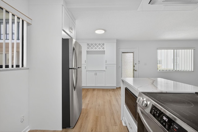 15036 Ashland Ln Unit 44, Delray Beach, FL 33484 - kitchen featuring stainless steel appliances, light wood-style flooring, white cabinets, and light stone counters
