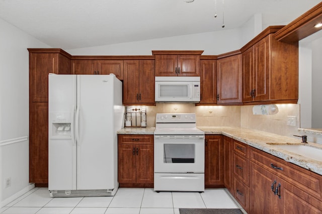 18541 Cherborg Dr Unit D, Boca Raton, FL 33496 - kitchen with white appliances, vaulted ceiling, light stone counters, light tile patterned floors, and brown cabinetry