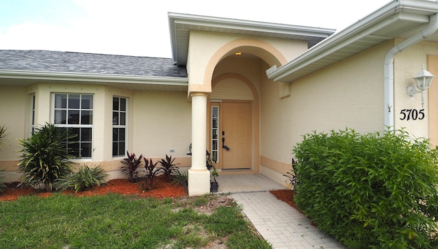 5705 NW Crocus Ave, Port Saint Lucie, FL 34986 - doorway to property featuring stucco siding and roof with shingles
