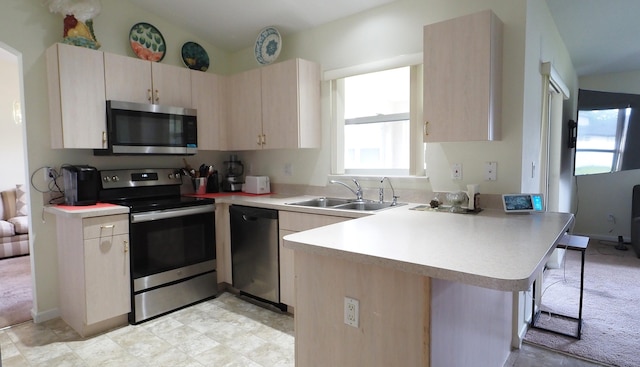 5705 NW Crocus Ave, Port Saint Lucie, FL 34986 - kitchen with appliances with stainless steel finishes, a peninsula, light countertops, light brown cabinets, and a breakfast bar