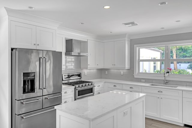 219 Claremont Ln, Palm Beach Shores, FL 33404 - kitchen featuring appliances with stainless steel finishes, wall chimney range hood, a center island, light stone counters, and white cabinets