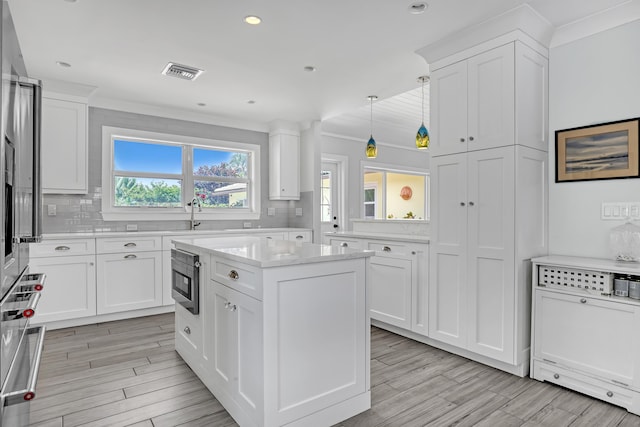 219 Claremont Ln, Palm Beach Shores, FL 33404 - kitchen featuring light countertops, decorative backsplash, hanging light fixtures, light wood-type flooring, and recessed lighting