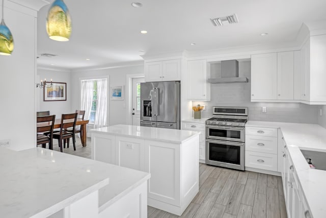 219 Claremont Ln, Palm Beach Shores, FL 33404 - kitchen with appliances with stainless steel finishes, wall chimney range hood, a kitchen island, backsplash, and white cabinetry