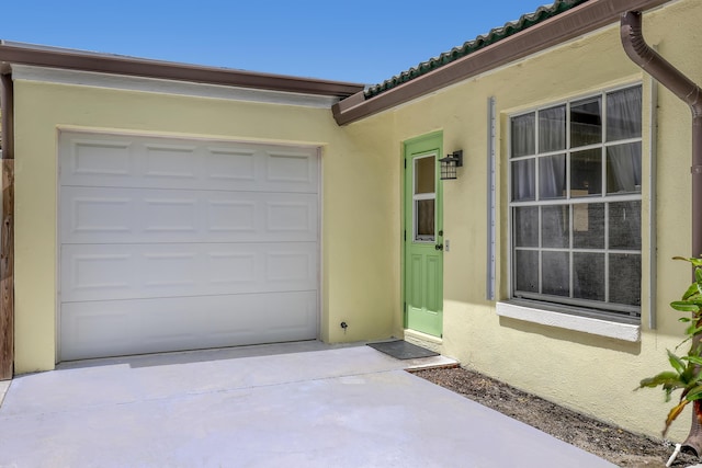 219 Claremont Ln, Palm Beach Shores, FL 33404 - property entrance with concrete driveway, stucco siding, a tile roof, and an attached garage