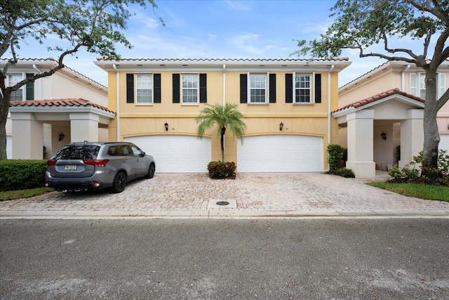 11 Live Oak Cir Unit 11, Tequesta, FL 33469 - view of front of property featuring driveway, a garage, a tiled roof, and stucco siding