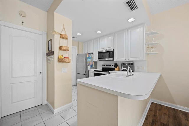 11 Live Oak Cir Unit 11, Tequesta, FL 33469 - kitchen with appliances with stainless steel finishes, a peninsula, white cabinetry, open shelves, and light countertops